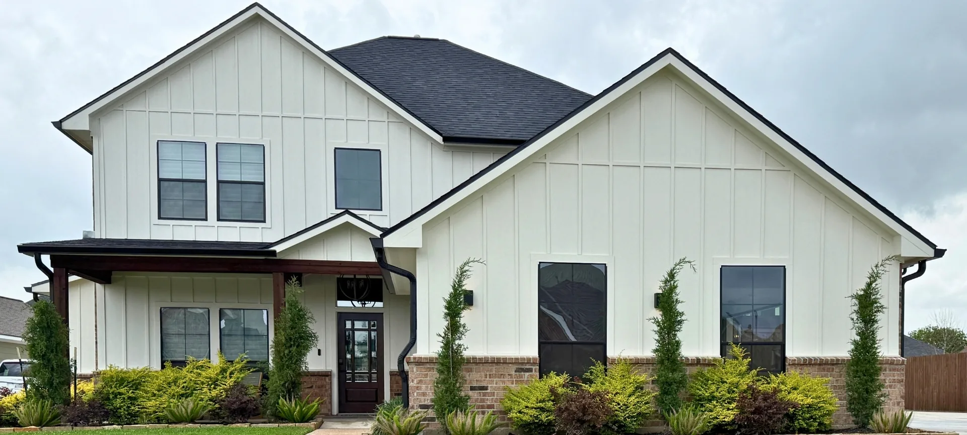 Freshly painted white board-and-batten home with dark roof by Horizon Restoration LLC in Baytown, TX